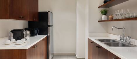 A modern kitchen with wooden cabinets, a black refrigerator, a microwave, and a sink.