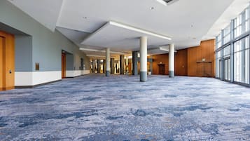 Un espacio interior amplio con alfombra estampada, pilares grandes y un techo alto con iluminación empotrada.