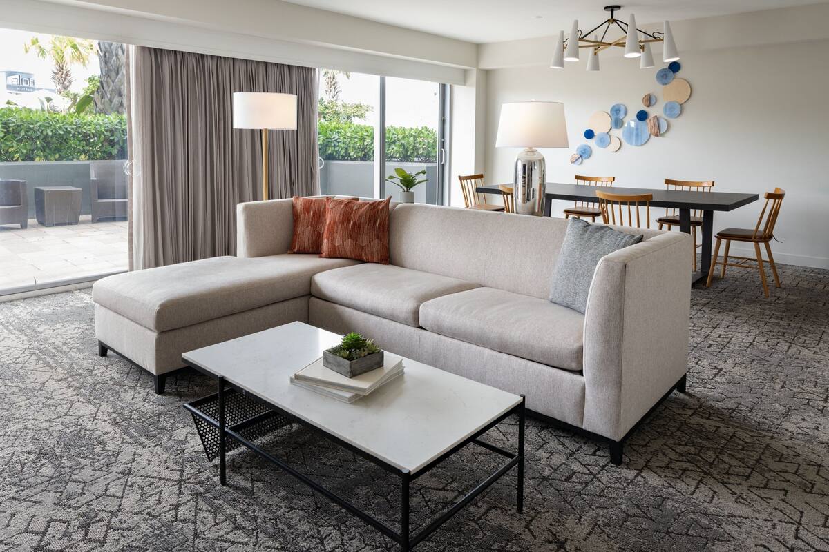 Un salon moderne comprenant un canapé d’angle, une table basse et un coin repas avec une table et des chaises.