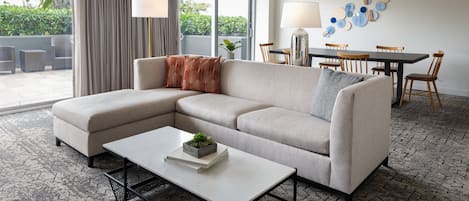 A modern living room with a sectional sofa, a coffee table, and a dining area with a table and chairs.