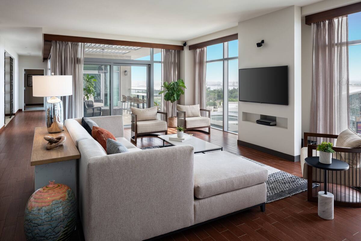 Une chambre d’hôtel moderne dotée d’un grand canapé, d’une table basse, d’une télévision et d’un balcon avec vue.