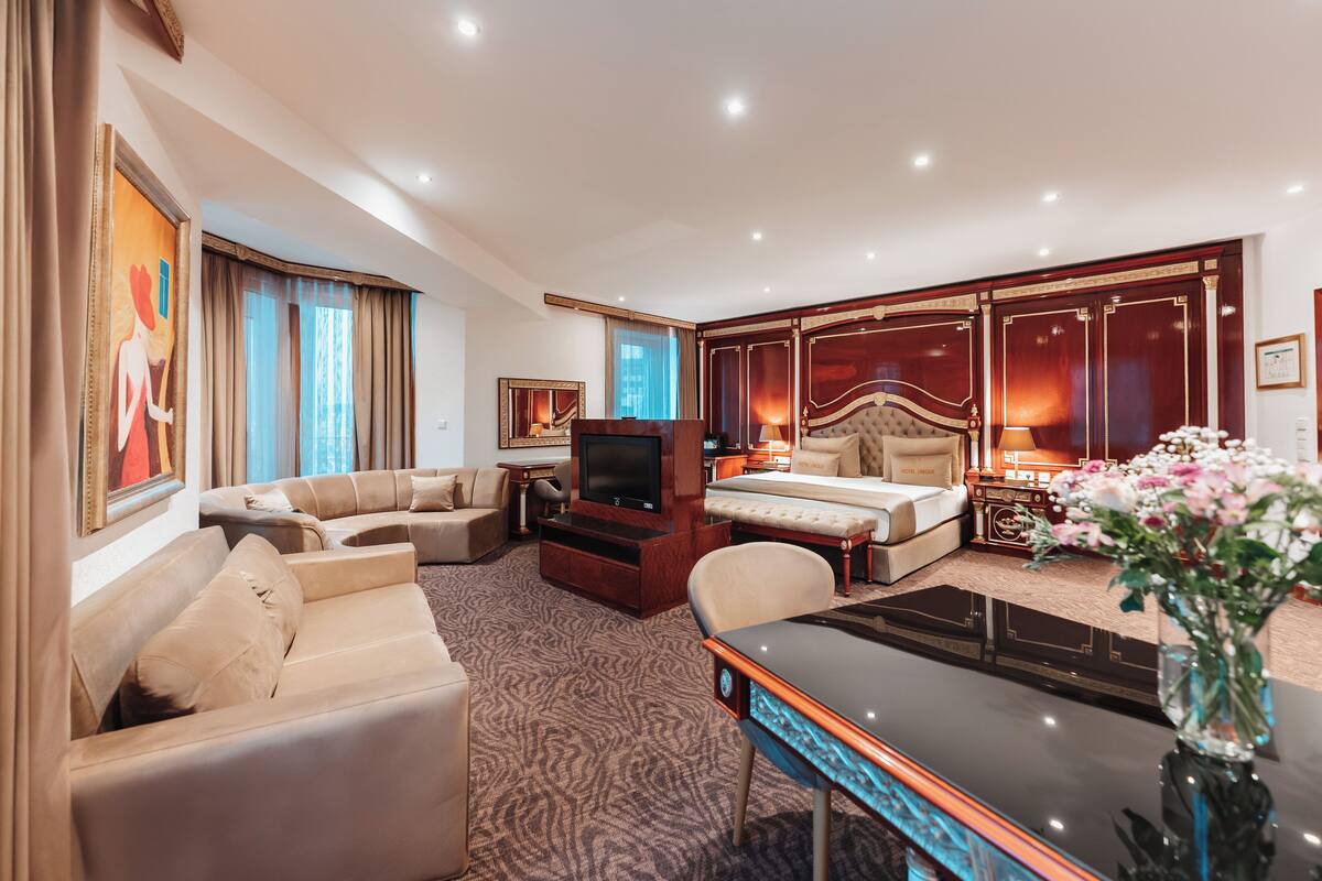 Une chambre d’hôtel équipée d’un canapé, d’un lit, d’une télévision, d’un bureau et d’un vase décoratif.