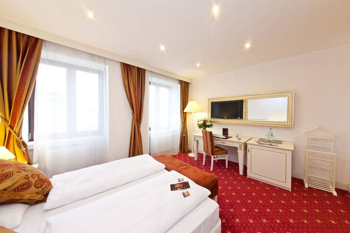 Une chambre d’hôtel équipée d’un lit, d’un bureau, d’une chaise et d’un téléviseur.