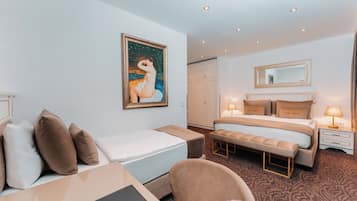 Ein Hotelzimmer mit einem Bett, einem Schreibtisch, einem Stuhl, einer Bank, einem Gemälde, einem Kleiderschrank und einem Spiegel.