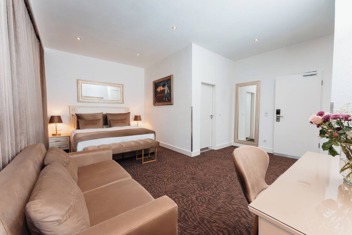 Une chambre d’hôtel avec un grand lit, un canapé, une table à manger et un miroir.