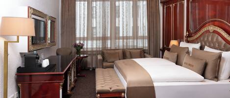 Une chambre d’hôtel avec un grand lit, un bureau avec un ordinateur, une chaise et une coiffeuse avec un miroir.