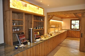 A breakfast bar with wooden cabinets, a coffee machine, and various food items. - Naturhotel Kitzspitz (Sankt Jakob in Haus)