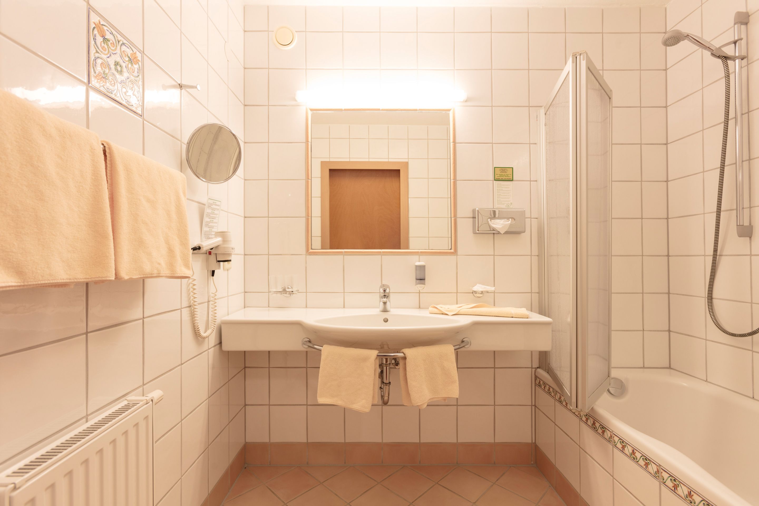 Un baño con lavamanos, espejo, toallero y ducha.