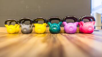 Une rangée de kettlebells aux couleurs vives sur un plancher en bois.