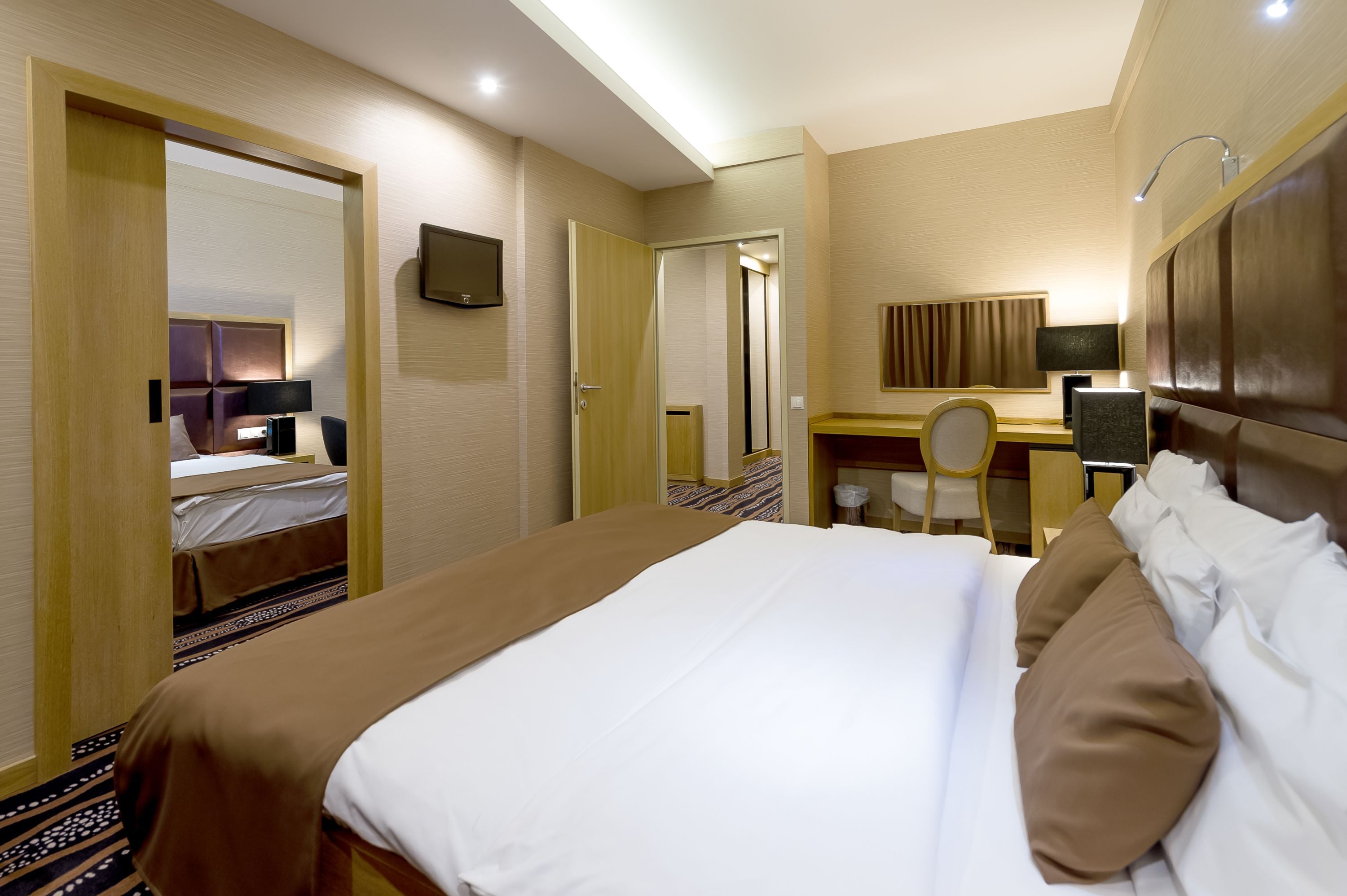 Una habitación de hotel con una cama, un escritorio, una silla y un televisor.