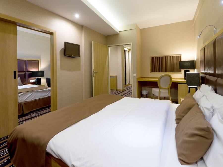Una habitación de hotel con una cama, un escritorio, una silla y un televisor.