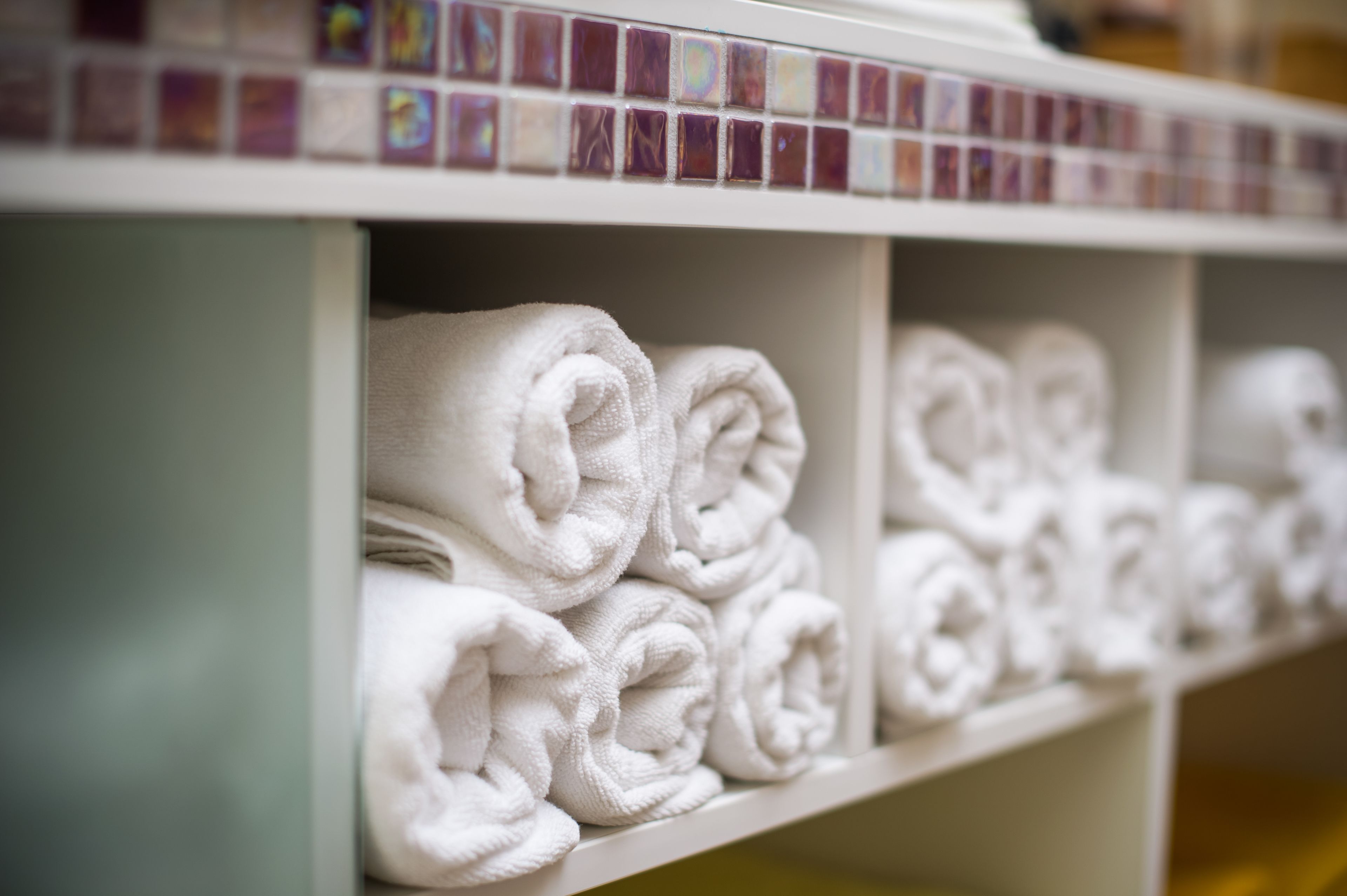 A row of neatly folded white towels on a shelf.
