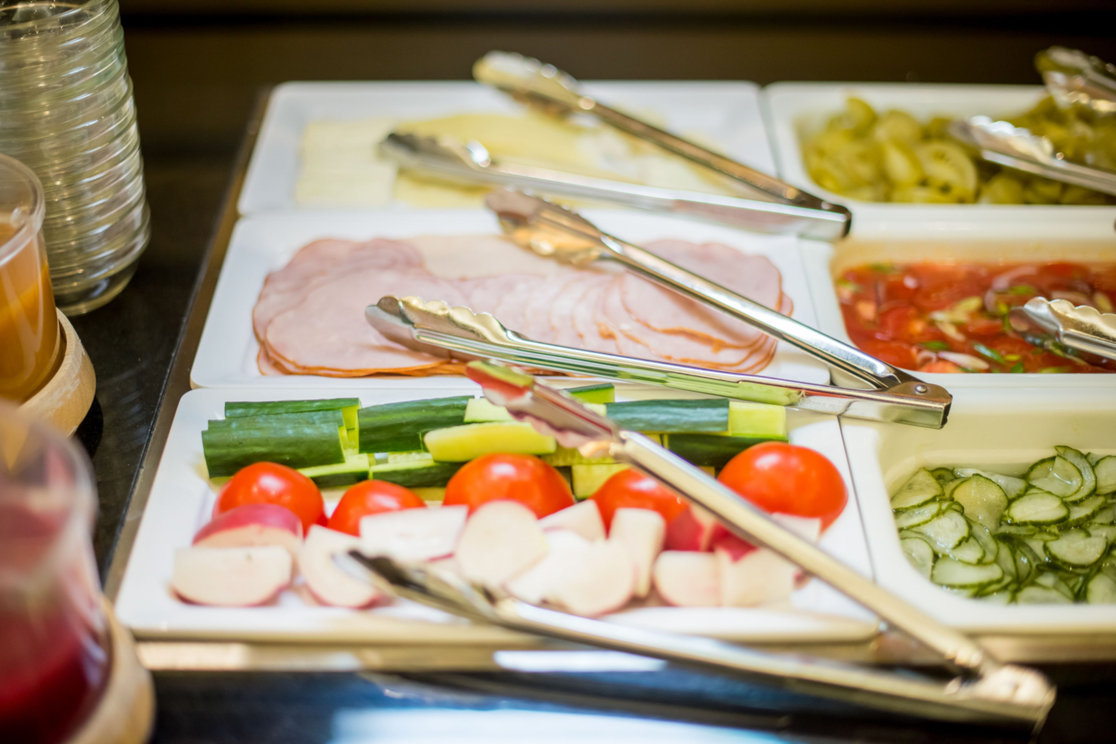 Ein Buffet mit verschiedenen Speisen, darunter Schinken, Gemüse und Salat.