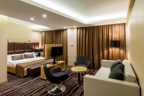 A hotel room with a bed, a desk, a TV, a sofa, and a small table. - Aquaticum Debrecen Thermal and Wellness Hotel (Debrecen)