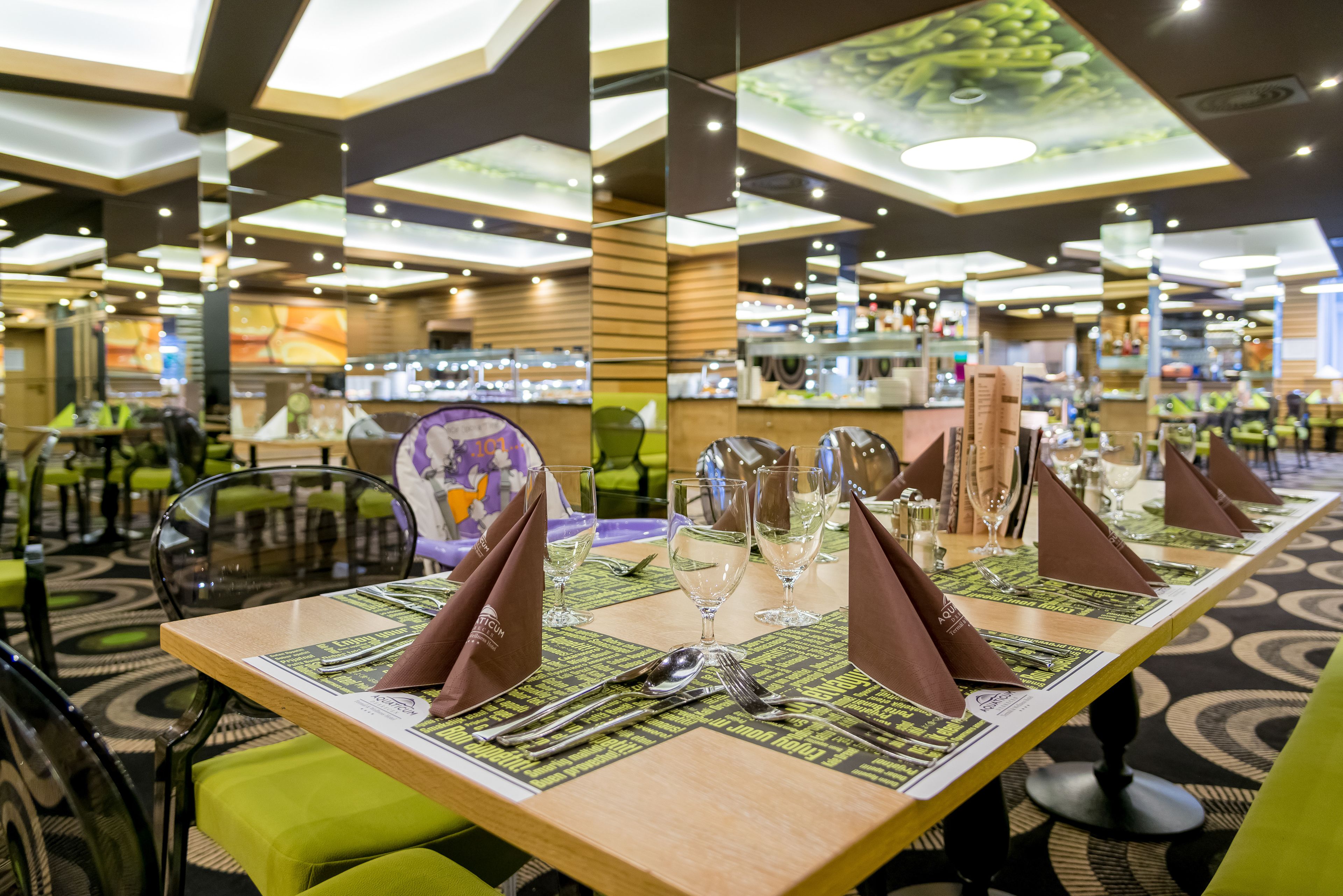 Un restaurante con una larga mesa de comedor dispuesta con varios puestos, incluyendo platos, cubiertos y vasos.