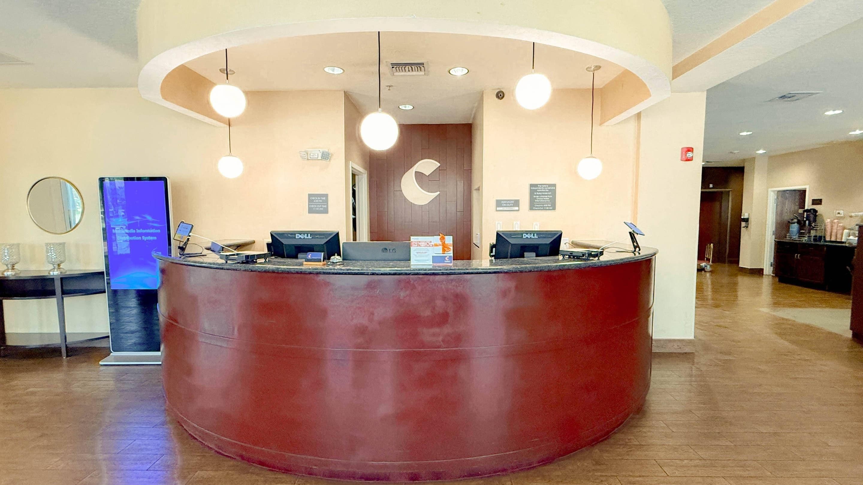 A reception desk with a curved design, multiple computer monitors, and overhead lighting.