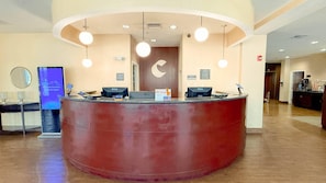 Un comptoir d’accueil au design incurvé, doté de plusieurs écrans d’ordinateur et d’un éclairage suspendu.