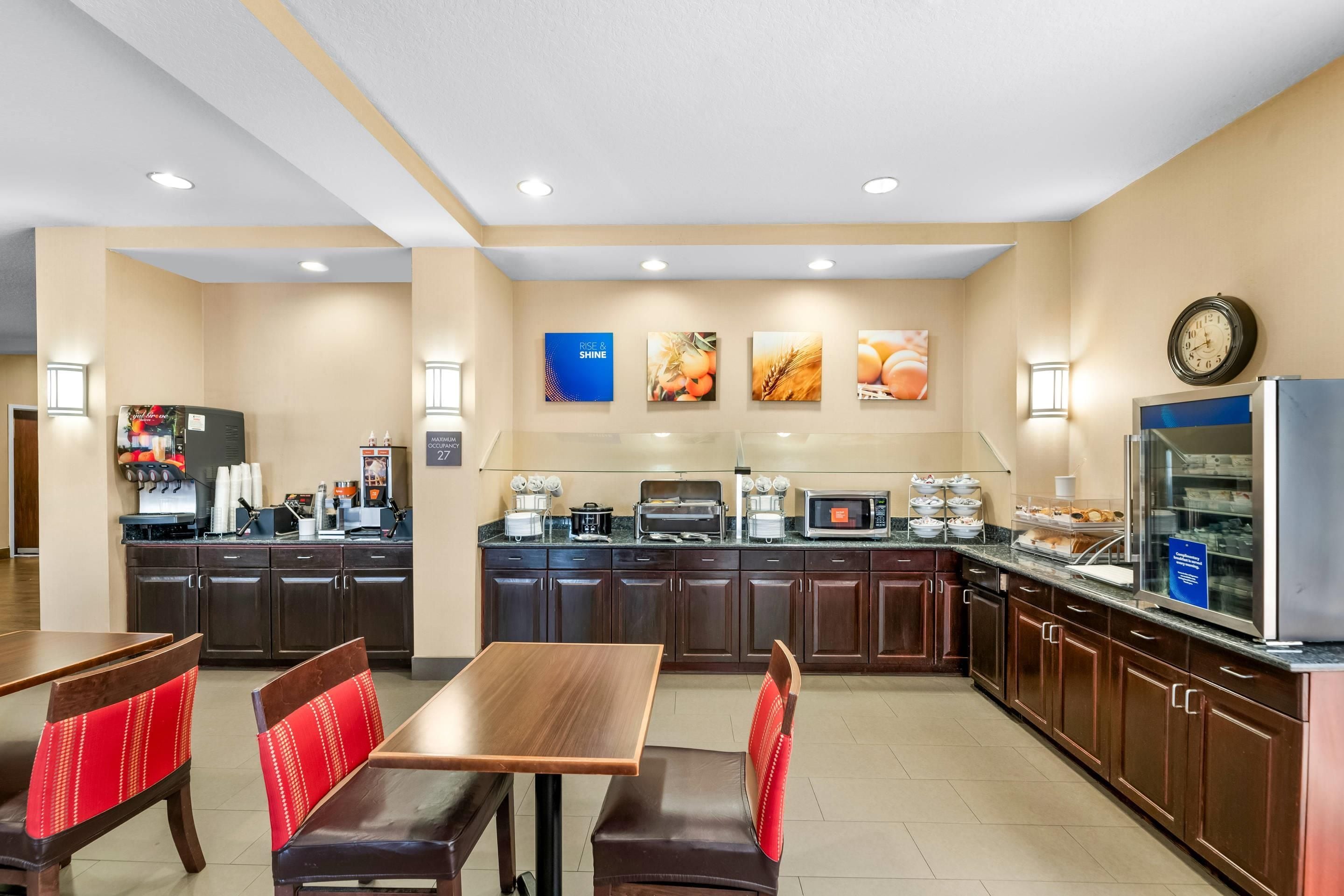 A hotel kitchen with a buffet, seating area, and a clock on the wall.