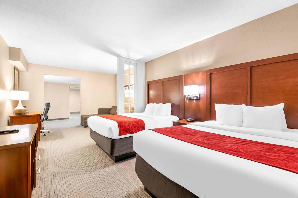 Een hotelkamer met twee bedden, een bureau, een stoel, een lamp en een kledingkast.