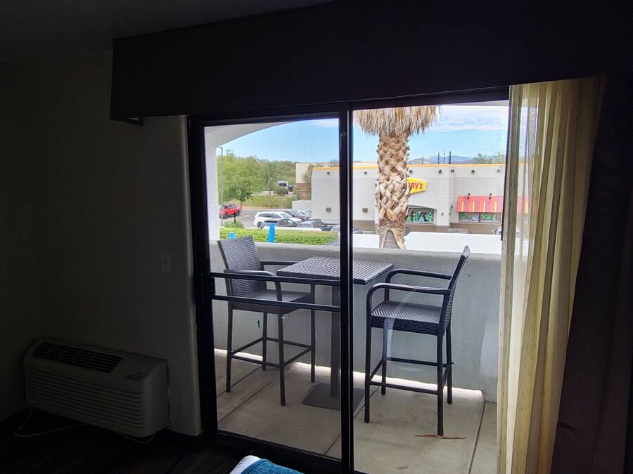 A room with a sliding glass door leading to an outdoor patio with two chairs and a table.