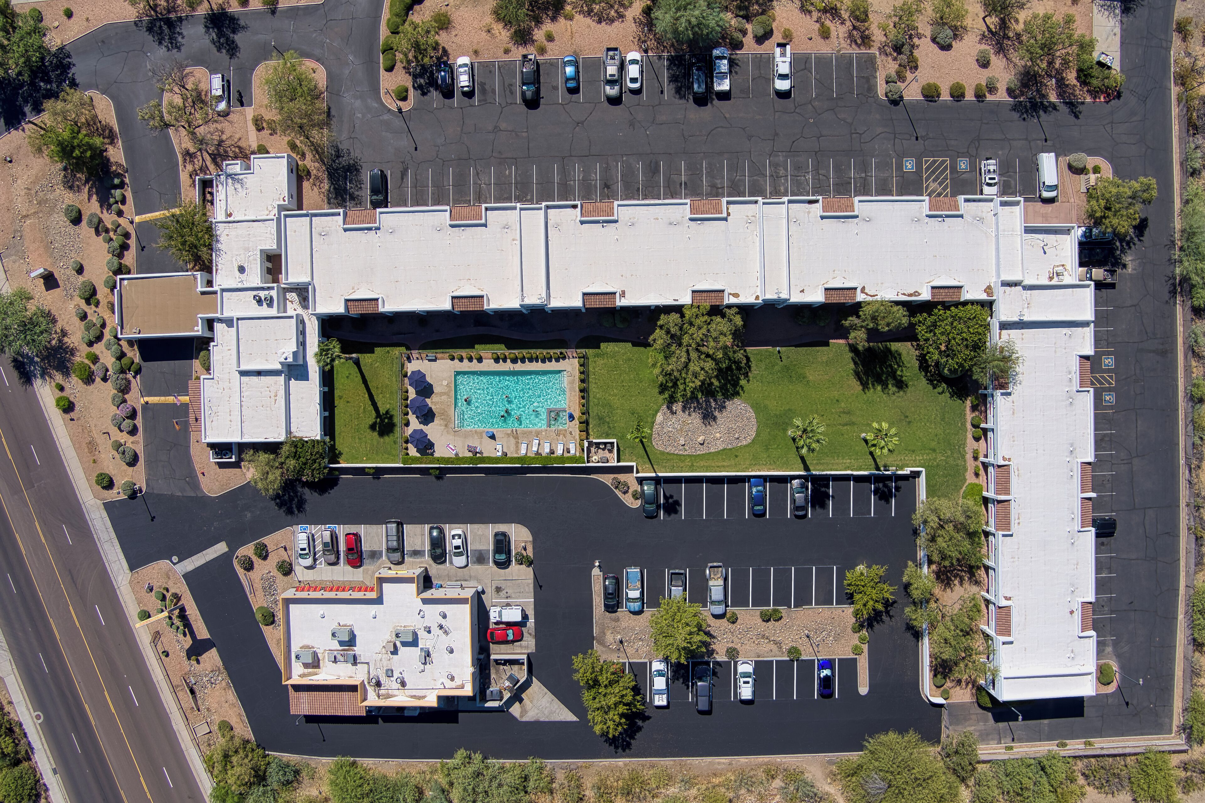 Vista aérea de un hotel con piscina, estacionamiento y zonas ajardinadas.