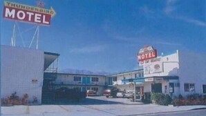 A motel with a prominent 'Thunderbird Motel' sign, a parking lot, and a building with a 'Breakfast' sign.