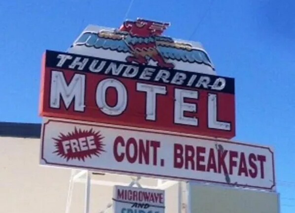 A motel sign with a thunderbird logo and a sign for free continental breakfast.