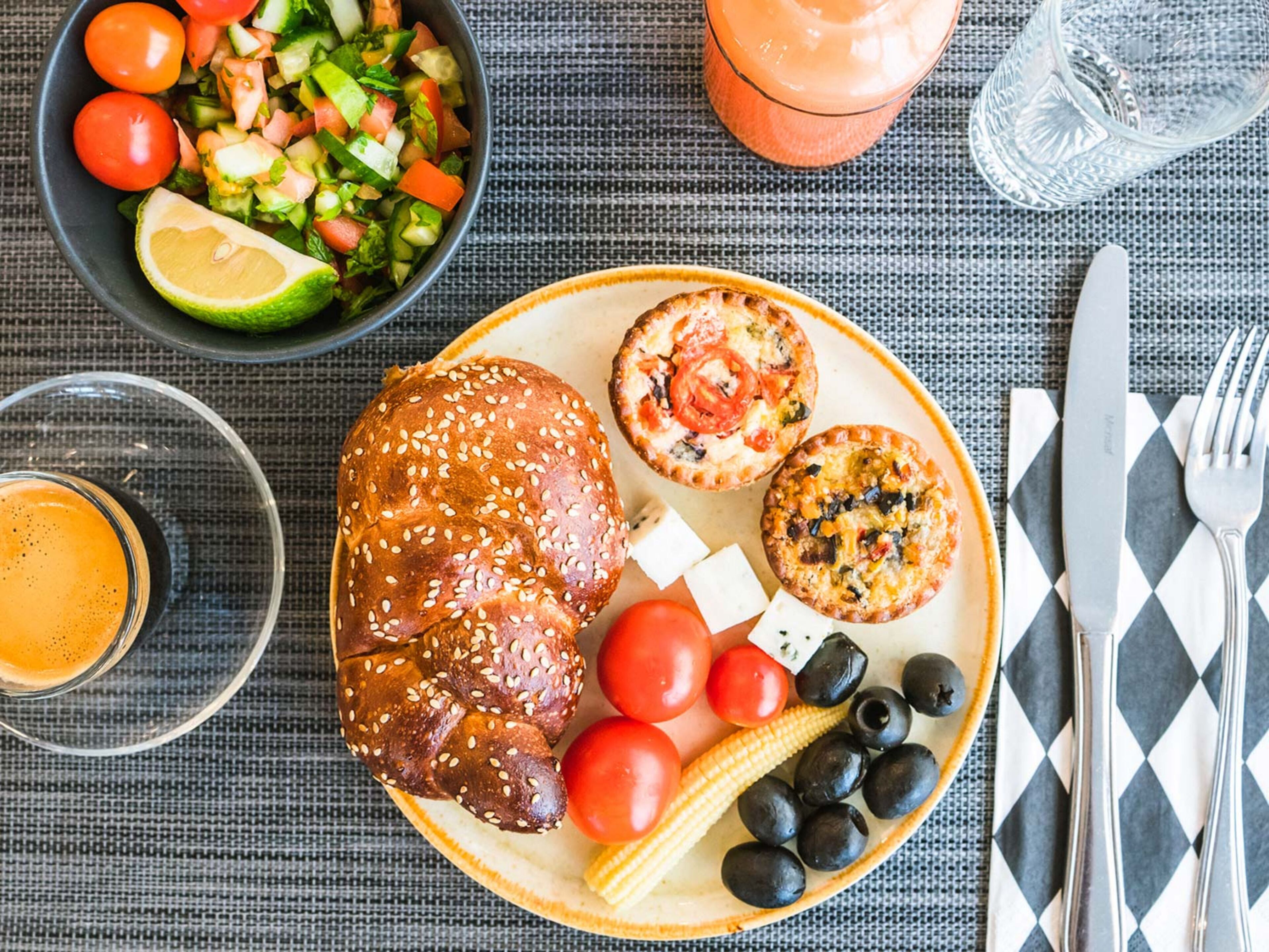 Un plato con carne asada, verduras y una bebida sobre una mesa.