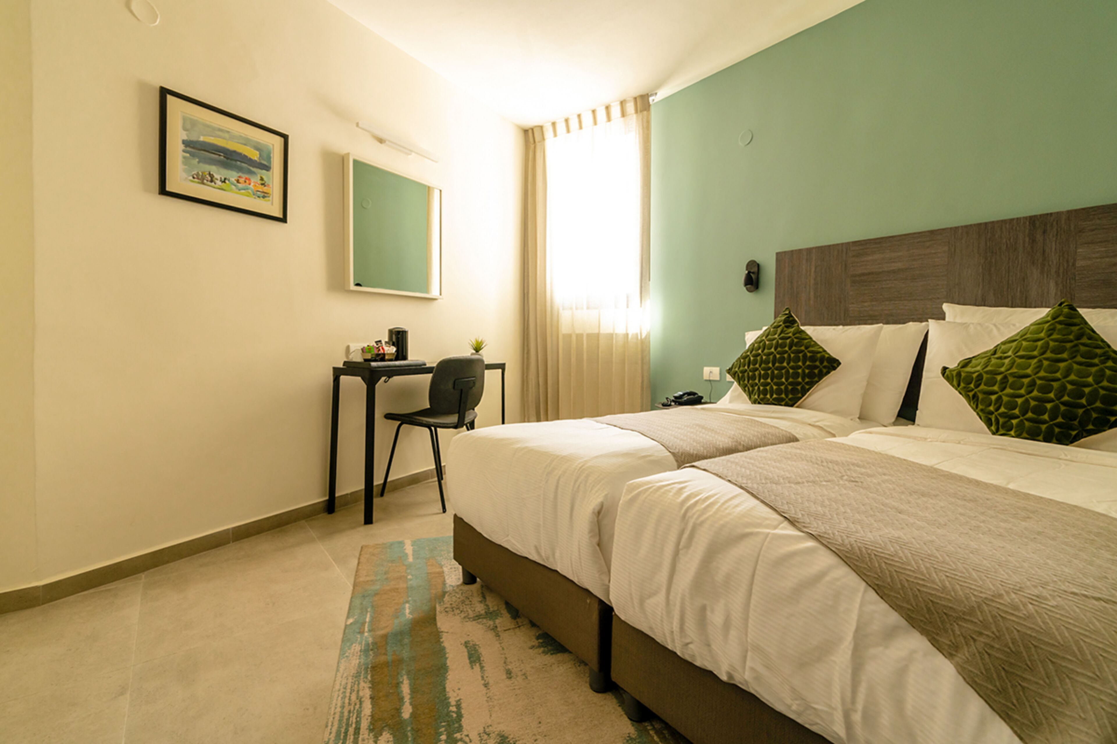 Ein Hotelzimmer mit zwei Betten, einem Schreibtisch und einem Stuhl.
