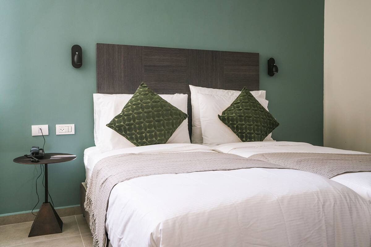 A neatly made bed with a wooden headboard, two pillows, and a bedside table with a lamp.