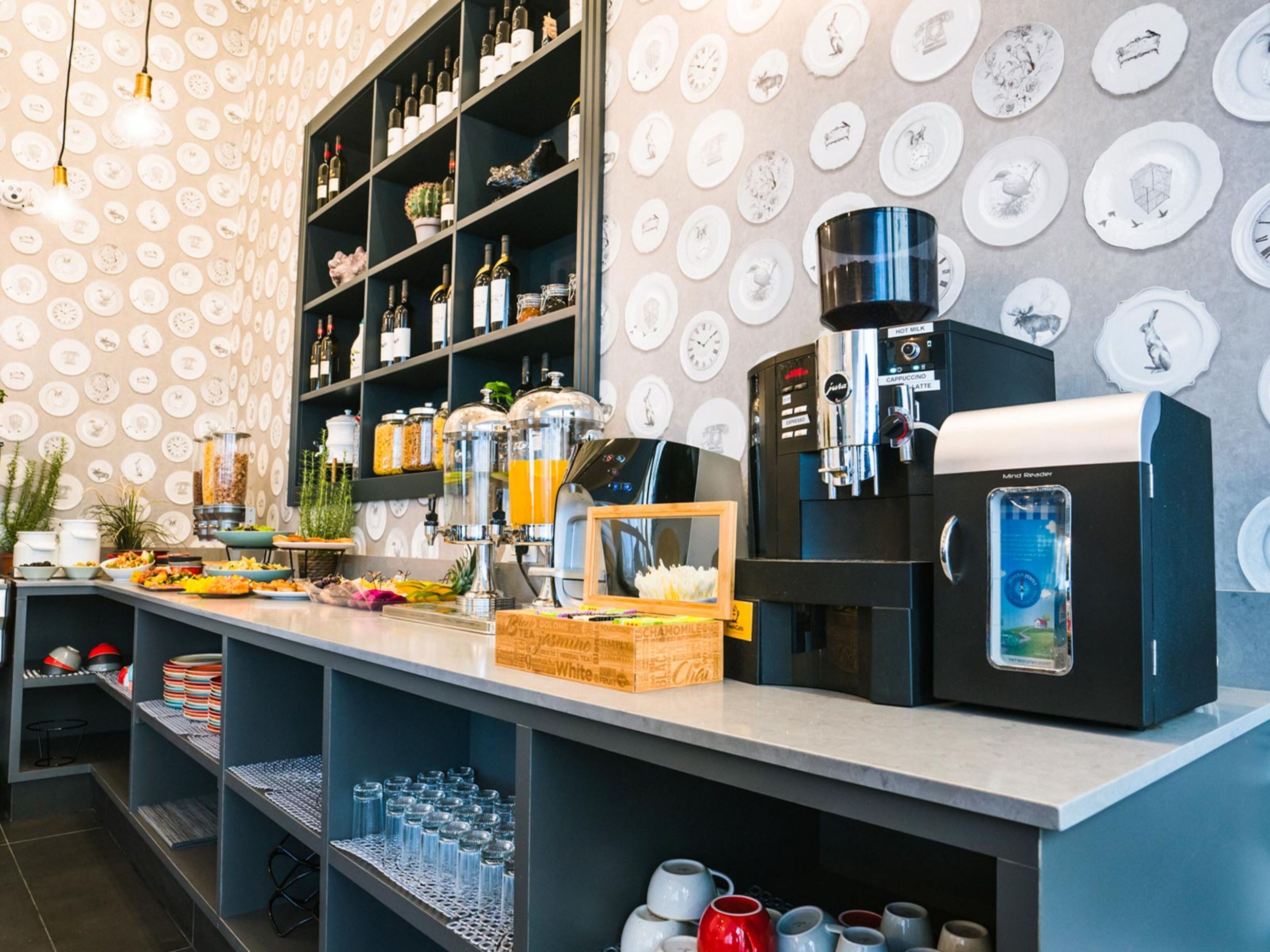 A café with a coffee machine, shelves with bottles, and a wall with plates.