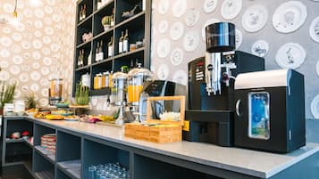 Una cafetería con una máquina de café, estantes con botellas y una pared decorada con platos.