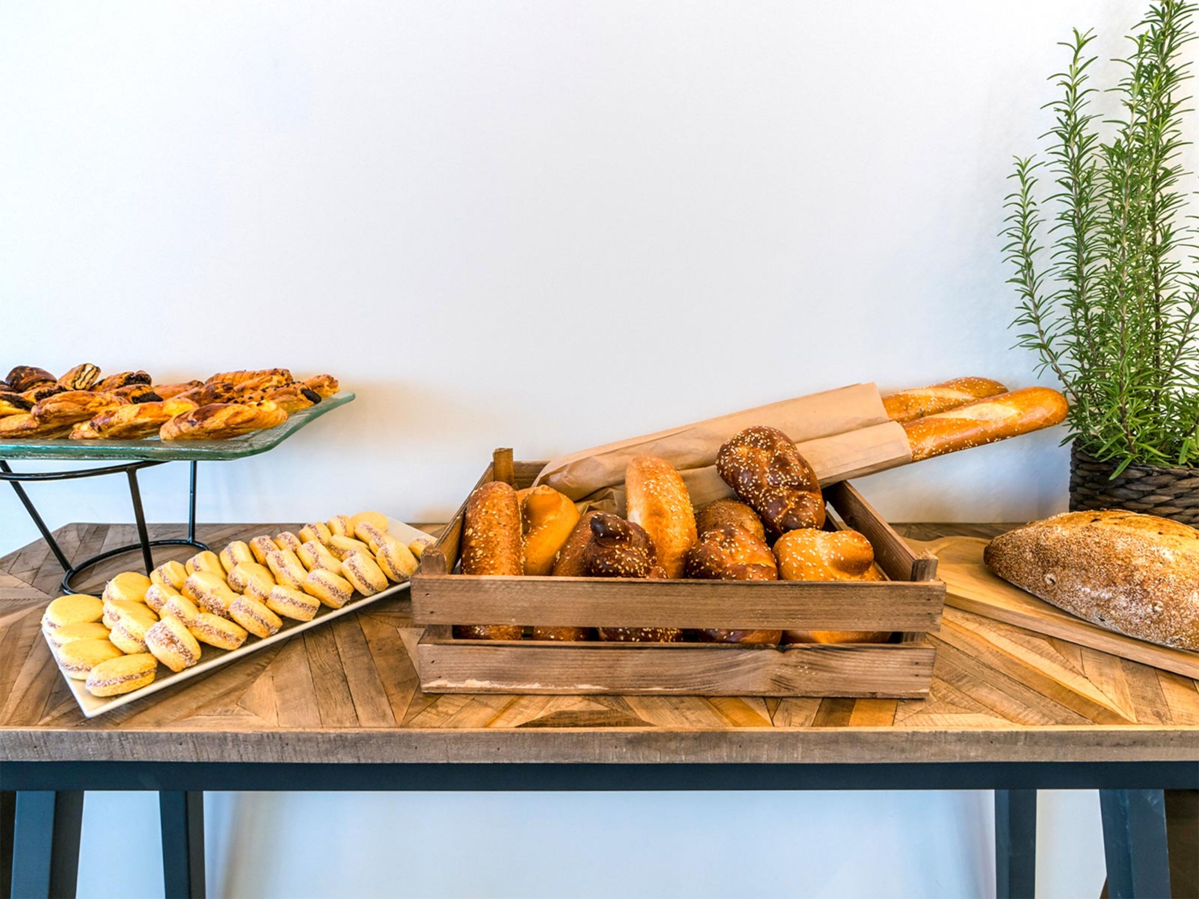 A wooden table with various baked goods, including bread and pastries, arranged on it.
