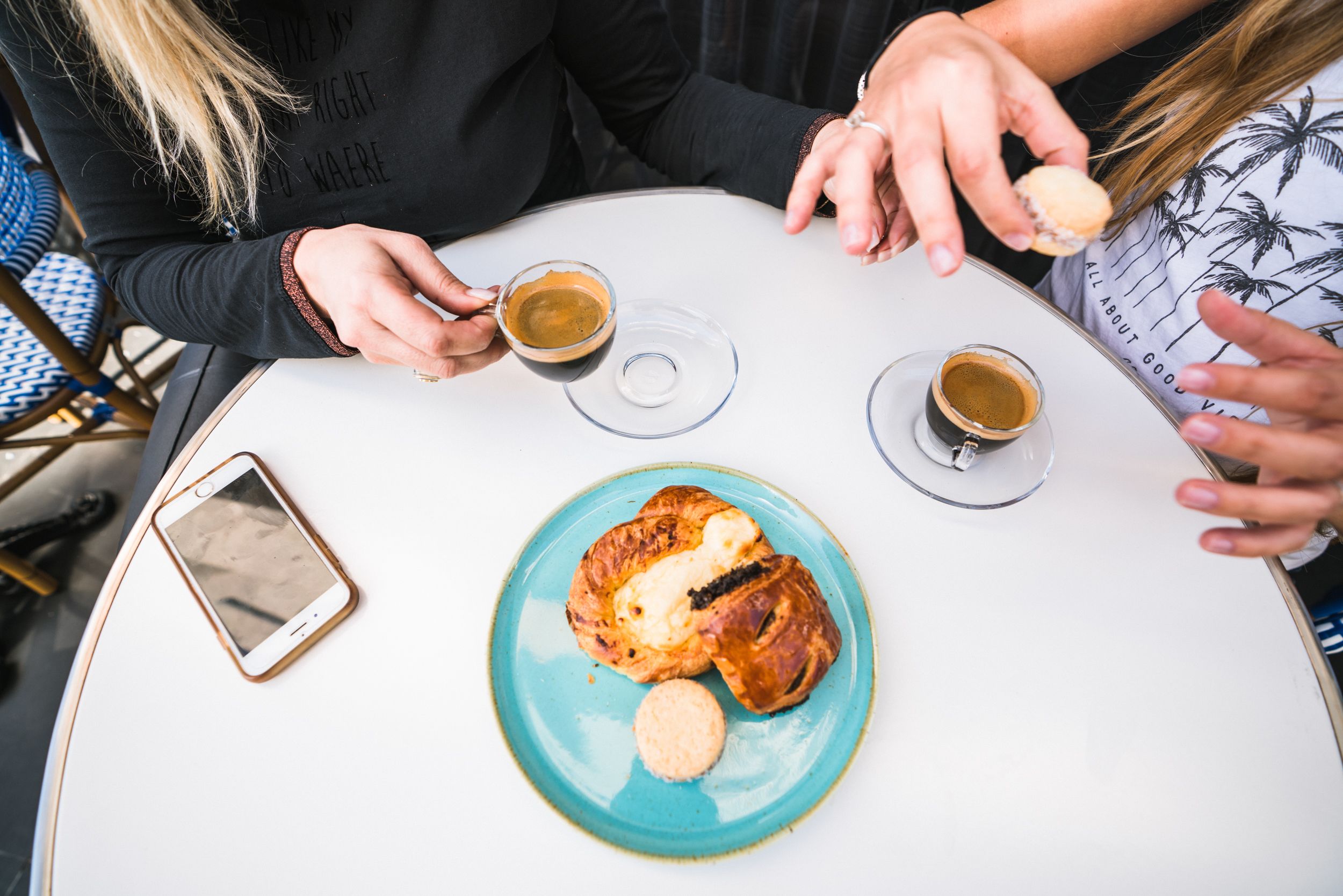 A table with two cups of coffee, a croissant, and a biscuit.
