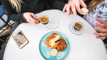 A table with two cups of coffee, a croissant, and a biscuit.
