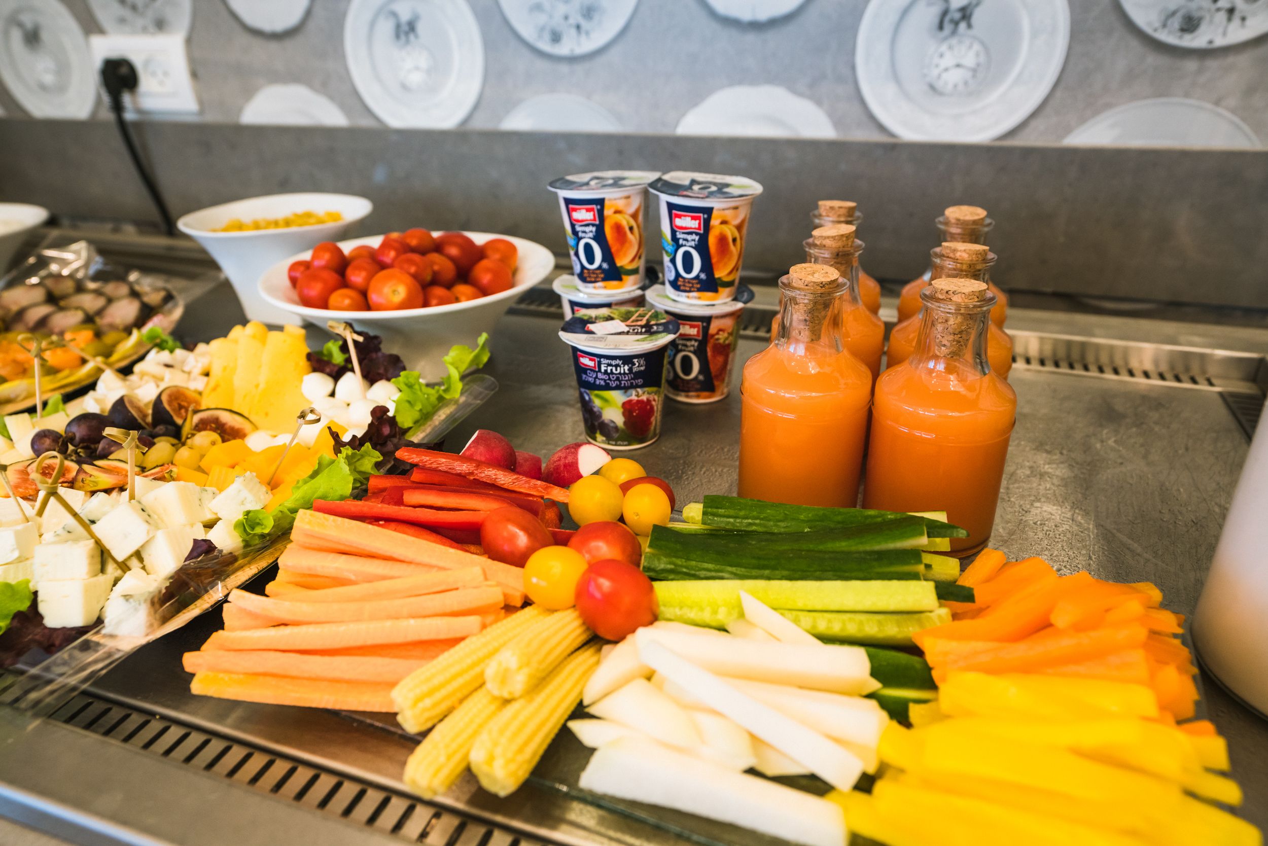 A buffet with various fruits, vegetables, cheeses, and beverages.