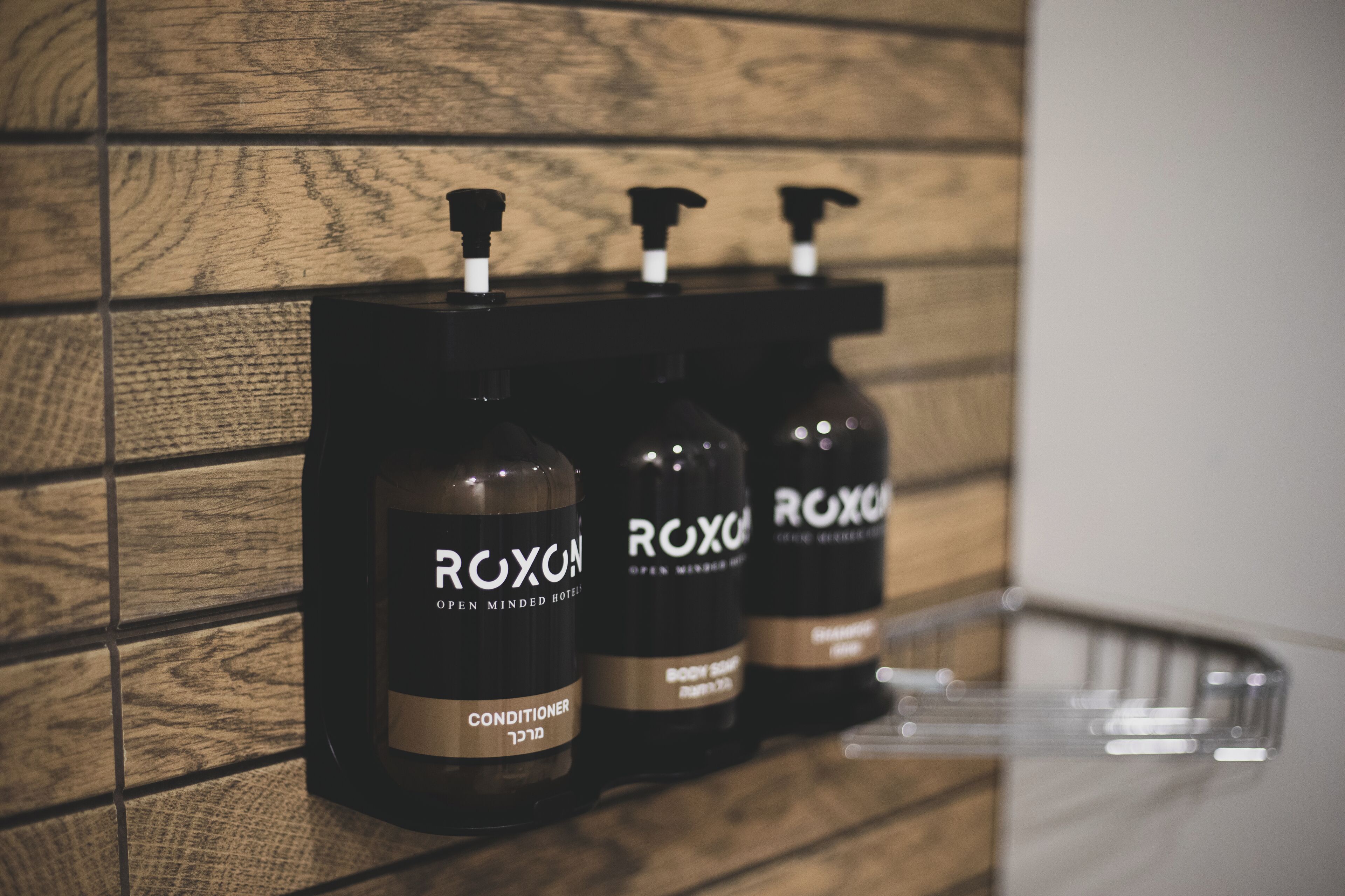 Three bottles of Roxox body wash on a wooden wall.