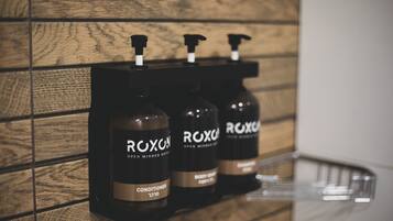 Three bottles of Roxox body wash on a wooden wall.