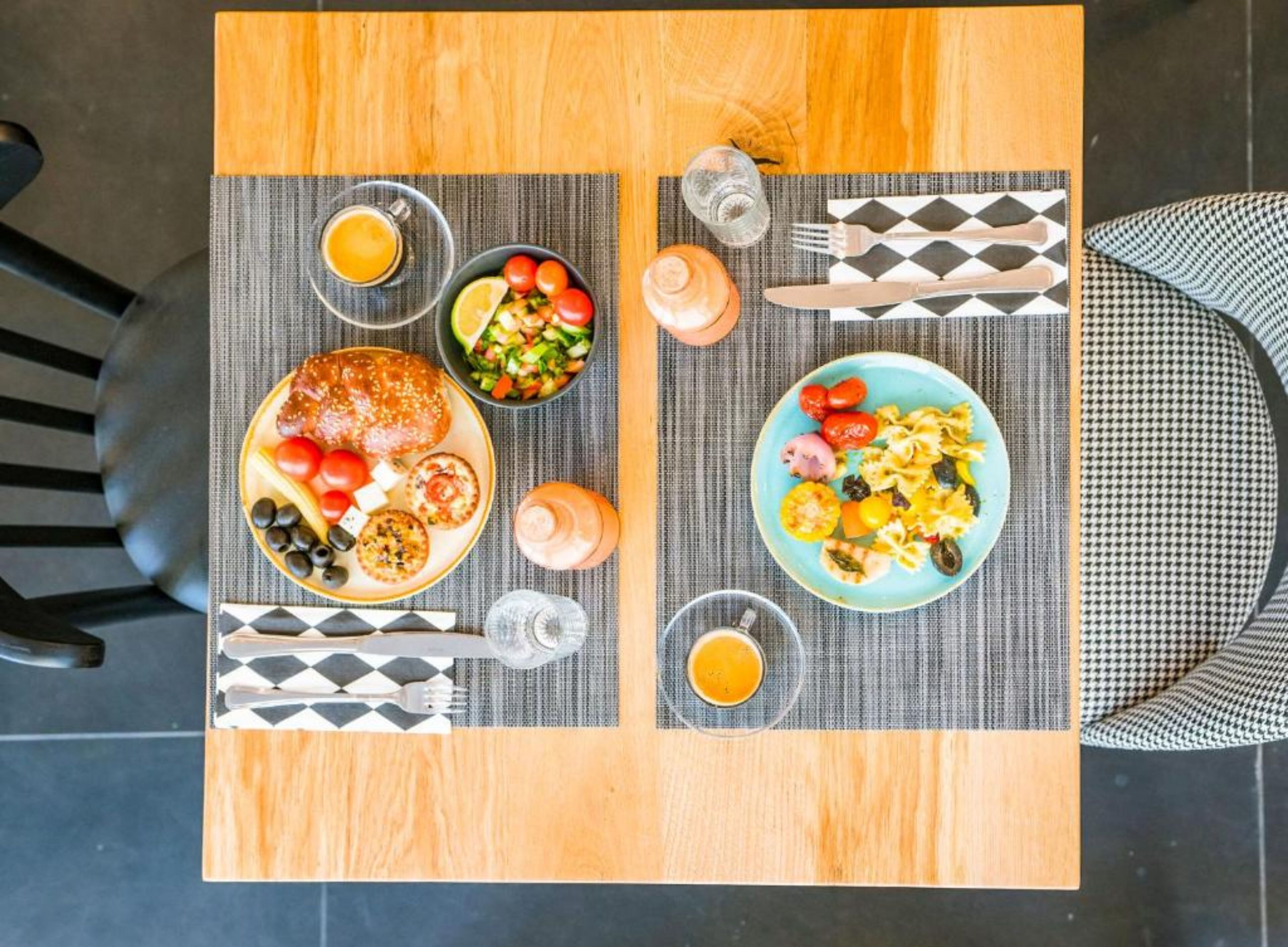 Una mesa de comedor con dos platos de comida, un vaso de zumo de naranja y un portavasos para servilletas.