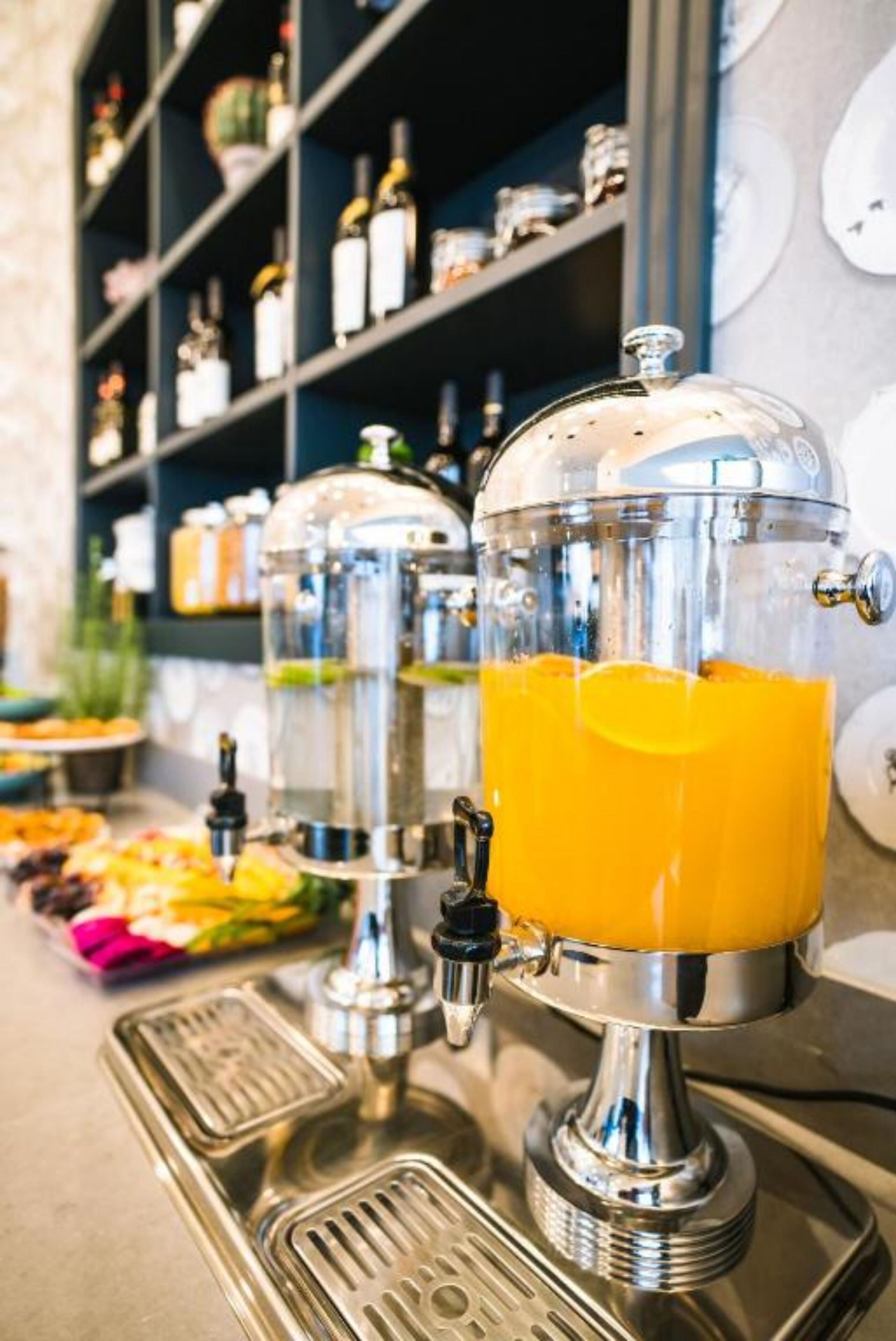A juice dispenser with a transparent dome and a metallic base, placed on a bar counter.