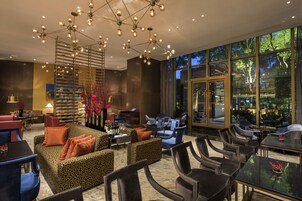 A modern lounge with a central seating area, a bar, and large windows offering a view of the outdoors.
