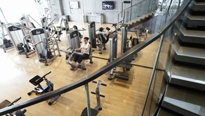 A gym with various exercise machines, a wooden floor, and a staircase. - InterContinental Shanghai Jing’ An by IHG (Shanghai)