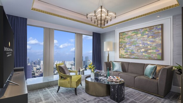 A modern hotel room with a city view, a large window, a sofa, a yellow armchair, a round coffee table, and a chandelier. - InterContinental Shanghai Jing’ An by IHG (Shanghai)