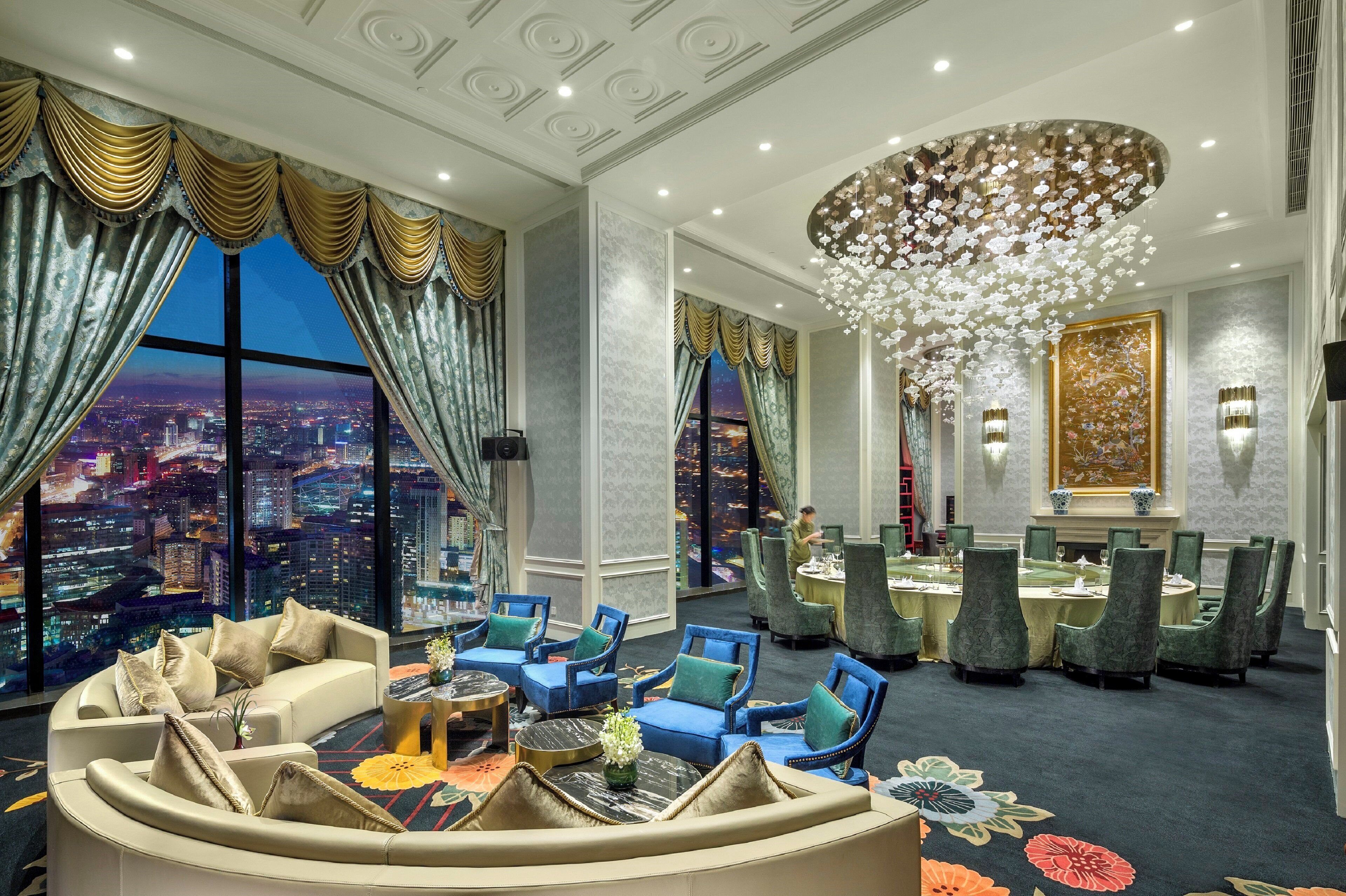 Una lujosa habitación de hotel con vista a la ciudad, un candelabro y un rincón de comedor.