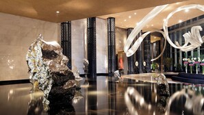 A modern lobby with reflective floors, large decorative columns, and abstract wall art. - InterContinental Shanghai Jing’ An by IHG (Shanghai)