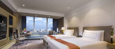 Habitación de hotel con dos camas, un sofá, un televisor y vistas a la ciudad.
