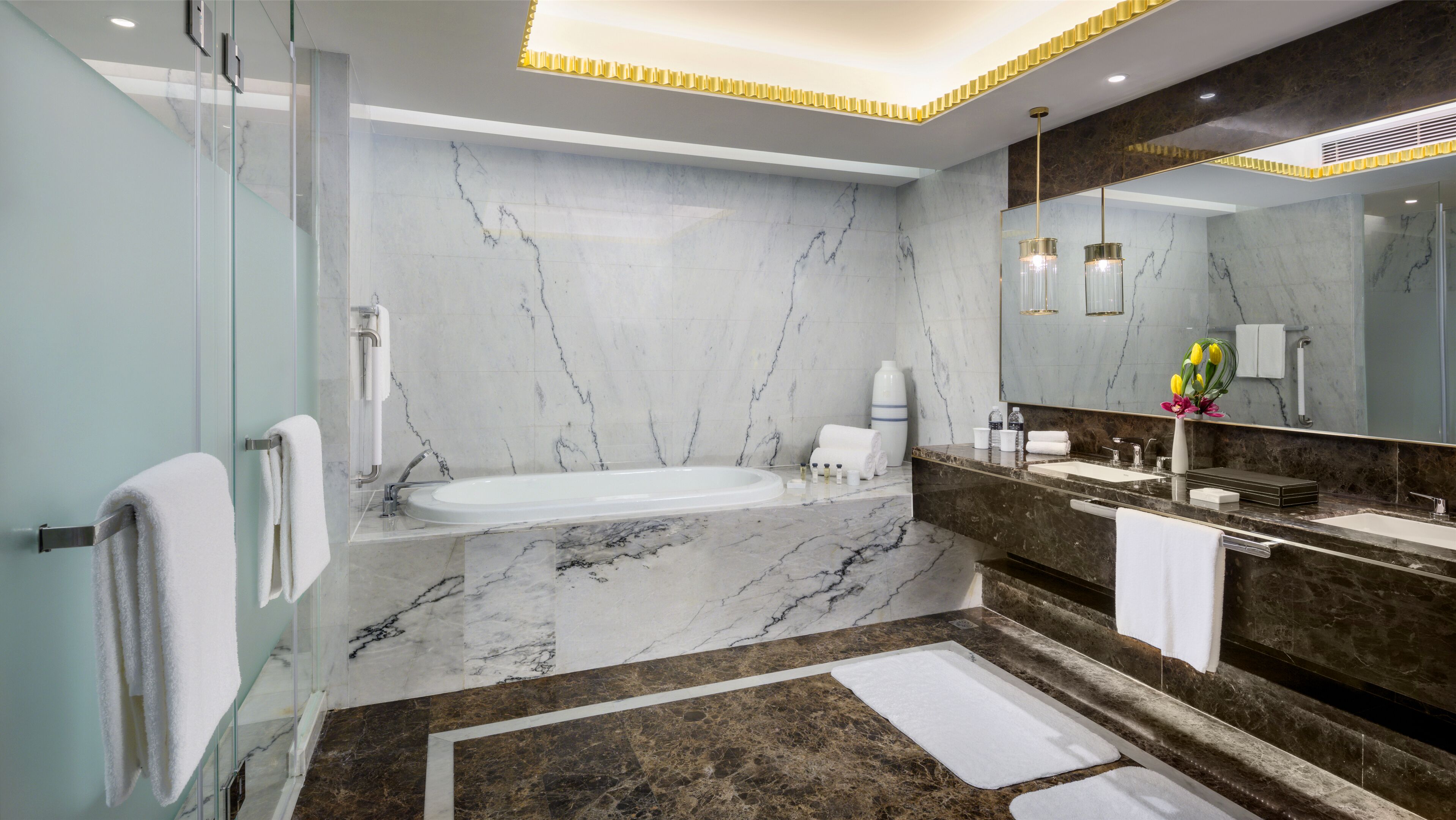 A modern bathroom with a marble floor, a bathtub, a large mirror, and a vanity with a sink and towel rack.