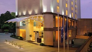 A modern hotel with a large entrance, multiple floors, and a covered outdoor area.
