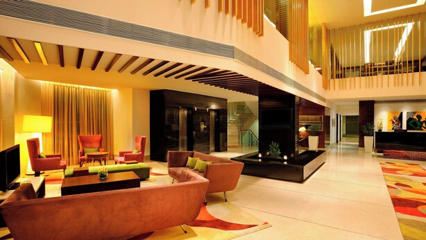 A spacious lobby with modern furnishings, a seating area, and a staircase leading to an upper level.