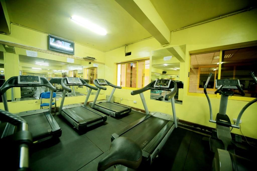A gym with treadmills, exercise bikes, and a television screen.
